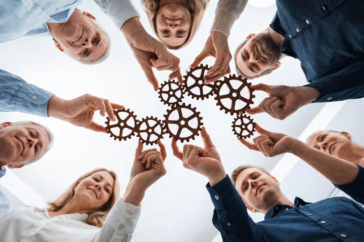 Bild på en grupp människor som håller i kugghjul som passar ihop